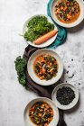 Вид зверху миски з смачним супом з капусти з морквою та чорним насінням, розміщеним на сірому столі біля серветок — стокове фото