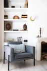 Assentos cinzentos confortáveis localizados perto da lareira e estante na acolhedora sala de estar no elegante apartamento — Fotografia de Stock