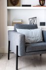 Комфортні сірі сидіння, розташовані біля каміна і книжкової полиці в затишній вітальні в стильній квартирі — стокове фото
