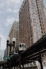 Angolo basso della strada della città di Chicago con treno pendolare in corso su un binario sopraelevato vicino ad alti edifici moderni — Foto stock