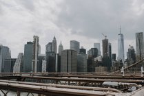 Небесна лінія Нью - Йорка з сучасними хмарочосами, які видно з мосту через річку в похмурий літній день. — стокове фото