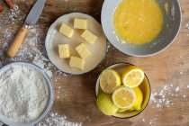 Top view of ingredients for cake recipe including bowl with flour and egg placed on dusted wooden table — Stock Photo