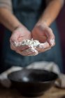 Cropped unrecognizable woman showing hands full of flour near black bowl while preparing pastry at home — Stock Photo