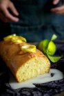 Coupé mains de femme méconnaissable préparation d'un délicieux gâteau au citron maison recouvert de glaçure et tranches de citron — Photo de stock