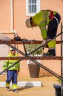 Gruppo di lavoratori in uniforme e caschi installazione pannelli fotovoltaici sul tetto di costruzione in legno vicino casa — Foto stock