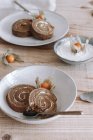 From above of sliced delicious homemade sweet roll cake with whipped cream and Physalis dried flowers served on plate on wooden table with ingredients — Stock Photo