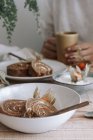 Desde arriba de rebanadas deliciosa torta de rollo dulce casero con crema batida y Physalis flores secas servidas en plato en mesa de madera con ingredientes - foto de stock