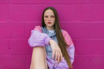 Trendy teenager sitting near pink wall — Stock Photo
