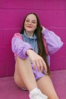 Trendy teenager sitting near pink wall — Stock Photo