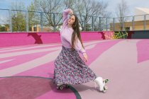 Стильна молода жінка на ковзанах позує на дитячому майданчику — стокове фото
