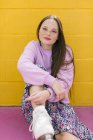 Adolescent branché avec patins à roulettes assis près du mur jaune — Photo de stock
