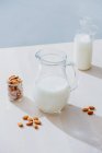Frasco de leite e amêndoas na mesa — Fotografia de Stock