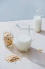 Jar of milk and oatmeal flakes on table — Stock Photo
