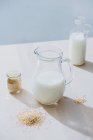 Банка молока и овсянка на столе — стоковое фото