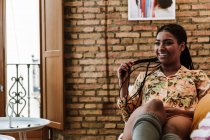 Happy ethnic woman sitting in living room — Stock Photo
