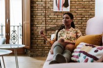 Glückliche ethnische Frau sitzt im Wohnzimmer — Stockfoto