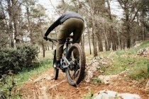 Ciclista in sella alla bicicletta su sentiero roccioso nella foresta — Foto stock