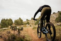 Ciclista in sella alla bicicletta su sentiero roccioso nella foresta — Foto stock