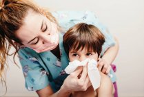 Little boy blowing nose in hospital on check up — Stock Photo