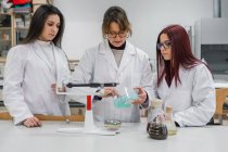 Female teacher and students conducting chemical experiment — Stock Photo