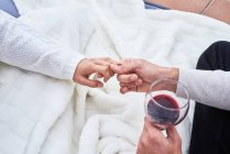 Von oben sieht man ein fröhliches junges Paar in Freizeitkleidung, das mit einem Glas Rotwein anstößt und gleichzeitig glückliche Momente miteinander genießt — Stockfoto