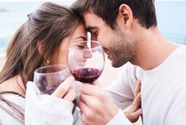 Von oben ein fröhliches junges Paar in Freizeitkleidung, das mit einem Glas Rotwein anstößt und gleichzeitig glückliche Momente miteinander genießt — Stockfoto