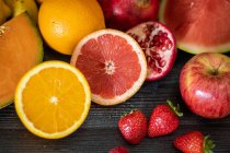 De arriba el manojo de las frutas distintas frescas llenas de las vitaminas puestas a la mesa negra de madera - foto de stock