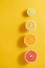 Top view of halves of assorted ripe citruses arranged in line on a yellow surface background — Stock Photo