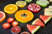 From above various peeled and cut healthy fruits and vegetables arranged on black lumber table — Stock Photo