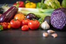 Купа різноманітних свіжих овочів, розміщених на чорному столі під час приготування здорової їжі на кухні — стокове фото