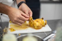 Cozinheiro irreconhecível amarrando pernas de codorniz marinada crua enquanto prepara delicioso prato na cozinha do restaurante — Fotografia de Stock