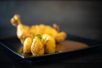 Vista superior da deliciosa galinha frita e batatas com molho e salsa colocados na mesa sobre a mesa de madeira preta no restaurante — Fotografia de Stock