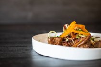 Carne frita selecionável servida com molho e ervas na placa cerâmica na mesa de madeira preta — Fotografia de Stock