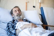 Ruhiger alter Mann mit Bart liegt unter Decke auf Krankenhausstation und schläft — Stockfoto