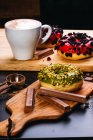 Assorted delicious doughnuts with glaze and toppings composed with chocolate bars and cup of coffee on wooden boards — Stock Photo