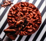 Overhead-Ansicht von ganzen süßen Schokoladenkuchen mit Schokoriegel auf gestreifter schwarz-weißer Oberfläche — Stockfoto