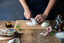 From above faceless chef cutting onion on cutting board while preparing appetizing dish at wooden table with bowl of rice and raw shrimps in composition with other ingredients at home — Stock Photo