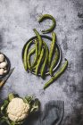 Vue de dessus des gousses vertes organiques sur plateau rond en métal avec champignons et chou-fleur sur la surface grunge gris — Photo de stock