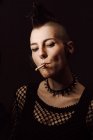 Mujer adulta con mohawk y piercing fumando cigarrillo - foto de stock
