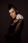 Mulher confiante com mohawk carregando rato branco no ombro e olhando para a câmera contra fundo preto — Fotografia de Stock