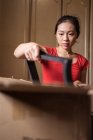 Етнічна леді розпаковує картонну коробку з розкладеними частинами стільця після доставки в затишному приміщенні вдома — стокове фото