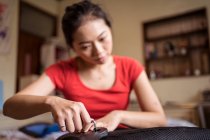 Молодая азиатская женщина с кольцом на мизинце, поворачивая винт во время установки ручки на стул дома — стоковое фото