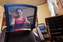 Dal basso donna etnica seduta sulla sedia e assemblaggio moderna nuova sedia in accogliente camera da letto a casa — Foto stock