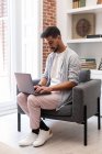 Bearded ethnic man using laptop while working on remote project at home — Stock Photo