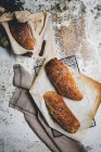 Composición rústica de arriba con panes aromáticos a bordo con toalla de lino y cuchillo en superficie de mala calidad - foto de stock