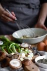 Mazzo di scalogno fresco e funghi messi sul tagliere vicino alle uova e semi di papavero contro casalinga raccolto mescolando ingredienti in ciotola — Foto stock