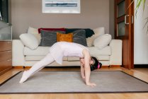 Side view of little girl in leotard doing exercise on floor during dance rehearsal at home — Stock Photo