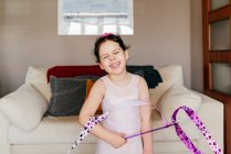 Nettes glückliches kleines brünettes Mädchen mit Schleife mit geschlossenen Augen beim rhythmischen Gymnastiktraining zu Hause — Stockfoto