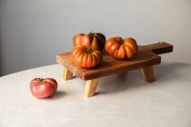 Зверху композиція з сирими червоними помідорами розташована на дерев'яній дошці на мармуровому столі — стокове фото