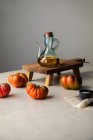Pot en verre avec huile d'olive placé sur un support en bois près de tomates rouges fraîches mûres sur la table de cuisine — Photo de stock